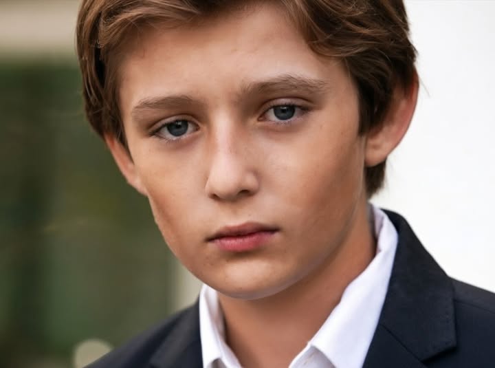 Young man in formal black suit and white shirt, portrait photograph related to Barron Trump upbringing privacy discussion