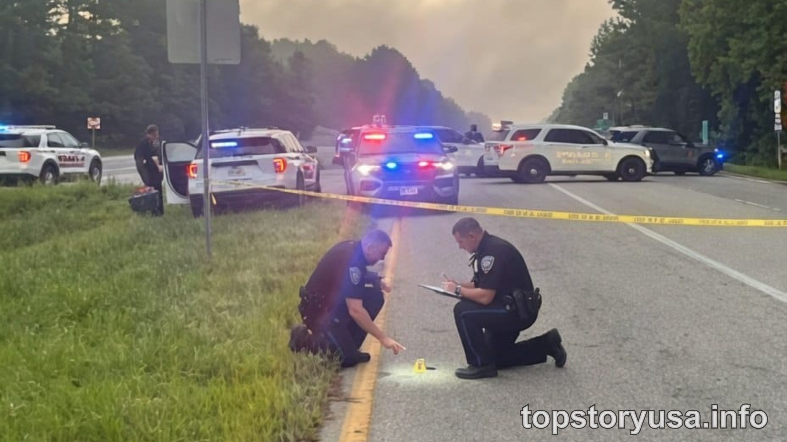Police officers investigate a police high-risk zone on a highway with multiple emergency vehicles and crime scene tape